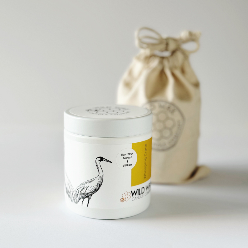 Minimal white candle container with lid featuring crane illustration and reusable linen bag packaging