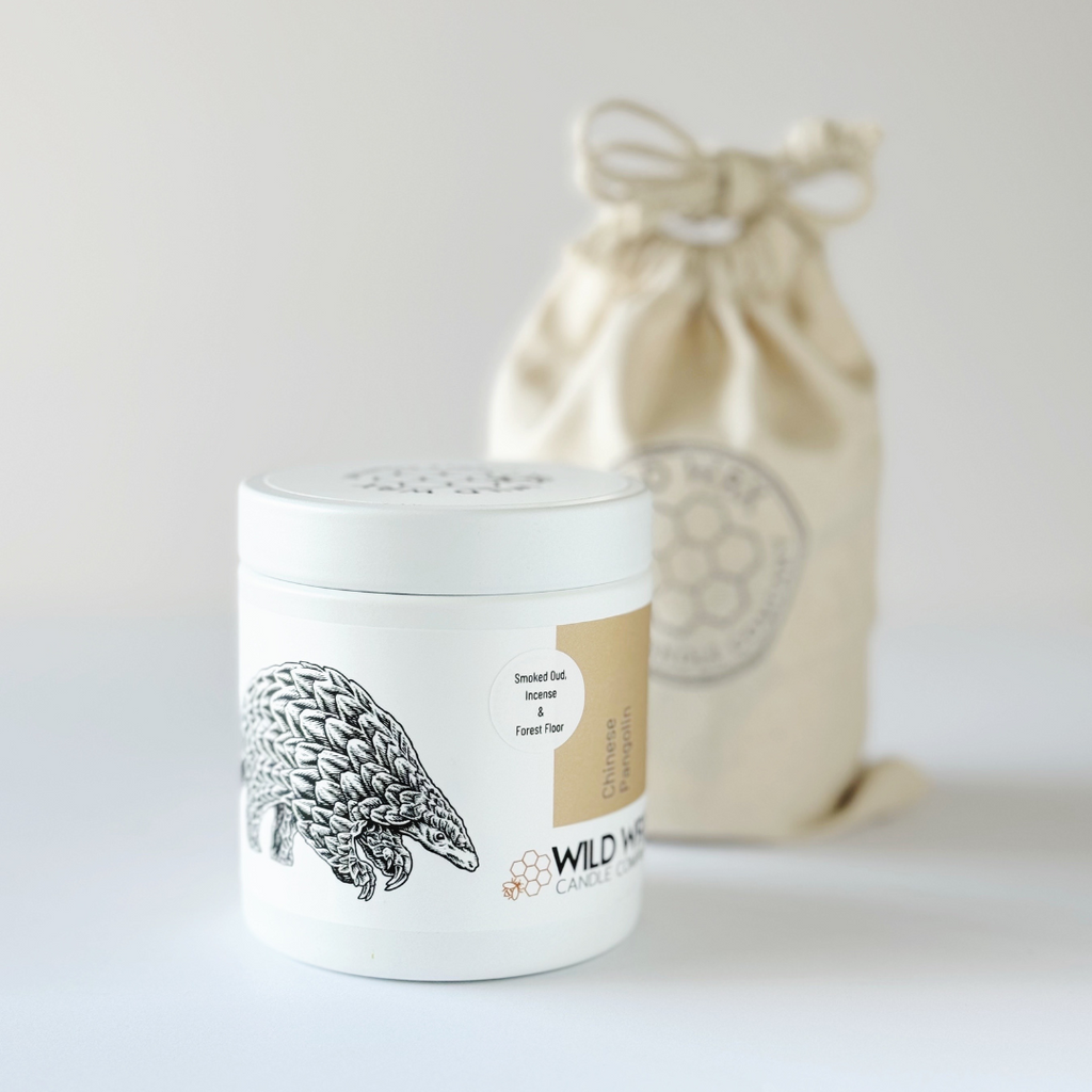 Minimal white candle container with lid featuring pangolin illustration and reusable linen bag packaging