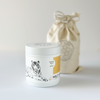 Minimal white candle container with lid featuring tiger illustration and reusable linen bag packaging