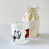 Minimal white candle container with lid featuring rhino illustration and reusable linen bag packaging