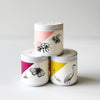 Three small container candles with lids and animal designs of a bumble bee, butterfly, and crane on the labels.